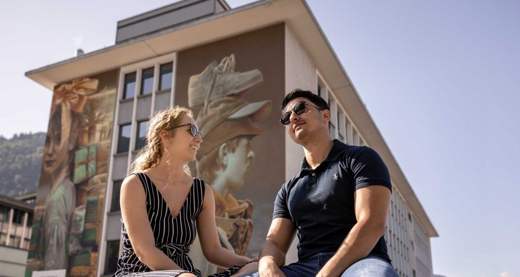 Street Art (© Flavio Schlegel) Mann und Frau sitzend vor einem Gebäude mit Street Art Fassade