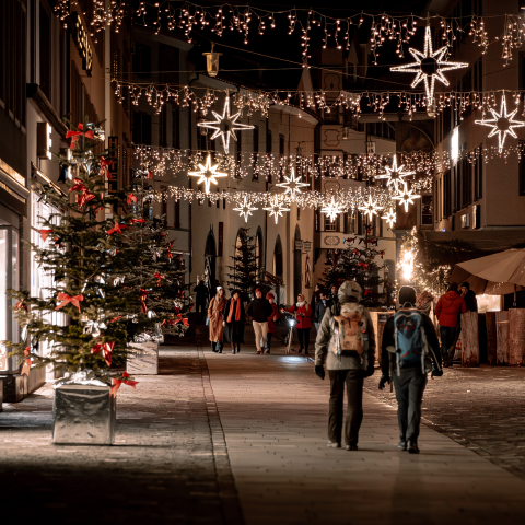 Chur im Advent (© Flavio Schlegel) Advent in Chur, Personen laufen durch Altstadt, Beleuchtung zwischen den Häusern