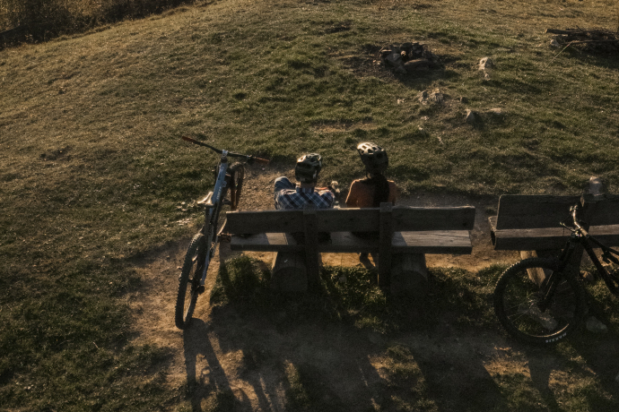 Sonnenuntergang auf einem Berg mit Sicht auf die Stadt Chur, auf einem Bank sitzen zwei Personen
