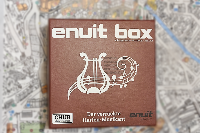 Enuit box (© Enuit) Braune Schachtel mit der Aufschrift „enuit box“ und einem weißen Leier- und Notenmotiv.