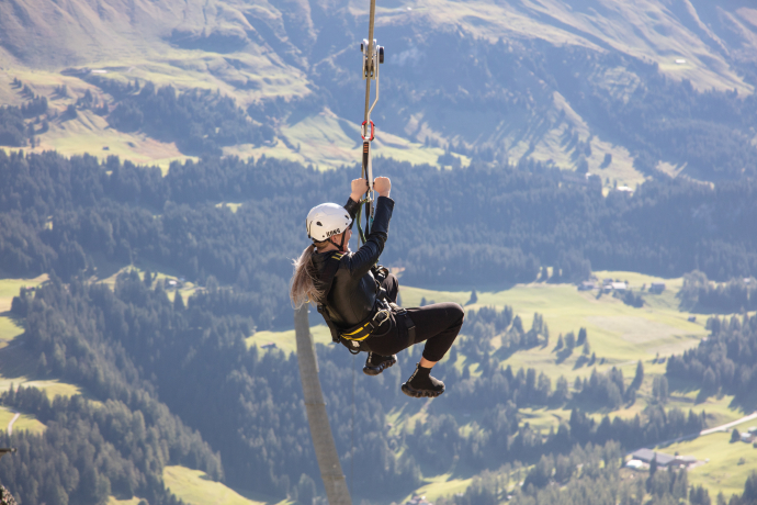 Zipline Pradaschier (© Pradaschier Erlebnisberg) Eine Person hängt in Pradaschier an der Zipline und fährt Richtung Tal