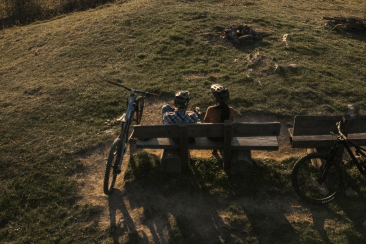 Sonnenuntergang auf einem Berg mit Sicht auf die Stadt Chur, auf einem Bank sitzen zwei Personen