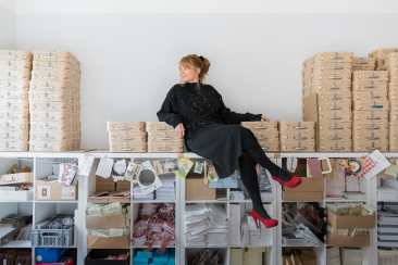 Künstlerin, welche auf einem Regal hockt in ihrem Atelier