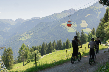 Eine Gruppe fährt unter der Brambrüesch-Bahn mit dem Trotti hinunter